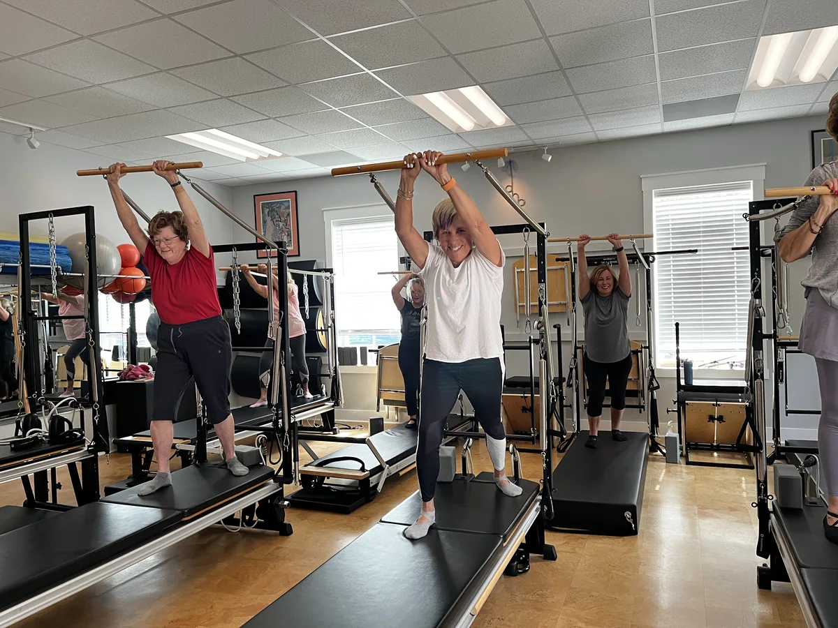 Full group Pilates class with arms raised on Tower equipment at Dancing Hammock